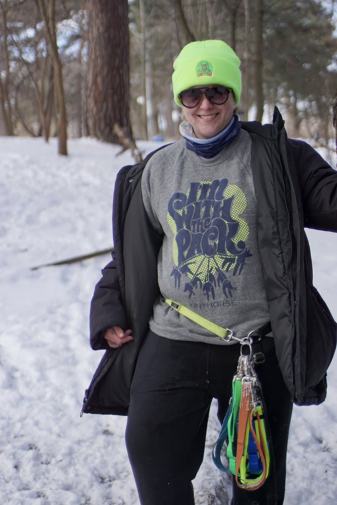 A woman wearing the "I'm with the Pack" Sweatshirt in a snowy forest