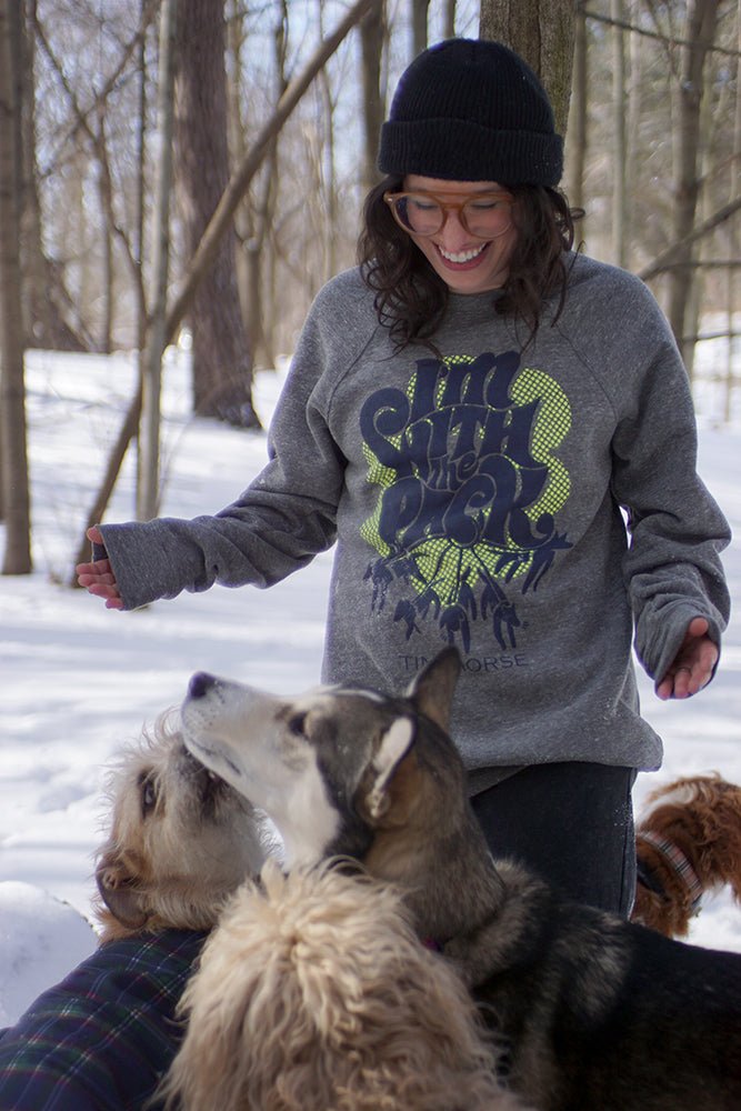 Woman wearing "I'm with the Pack" Sweatshirt walking 3 dogs in a snowy forest 