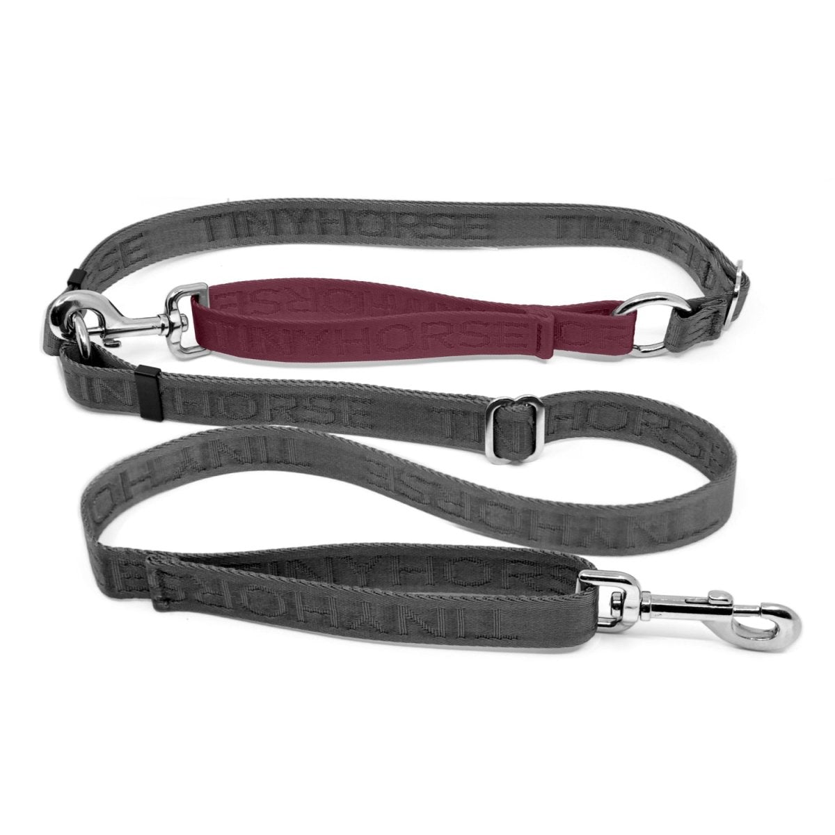 Adjustable hands-free dog leash with traffic handle. Grey with a burgundy colour accent in front of the hips. Attach more dogs using the rings sewn into the waist. Made of nylon embossed with “Tinyhorse.”