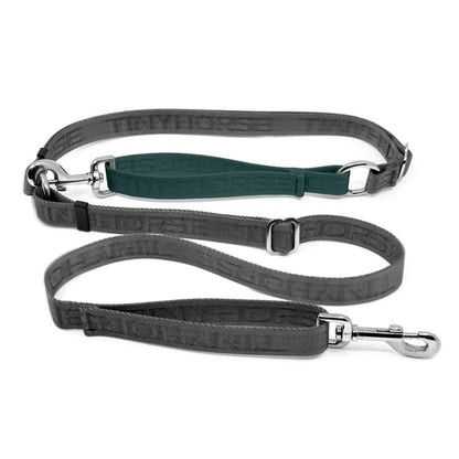 Adjustable hands-free dog leash with traffic handle. Grey with a green colour accent in front of the hips. Attach more dogs using the rings sewn into the waist. Made of nylon embossed with “Tinyhorse.”