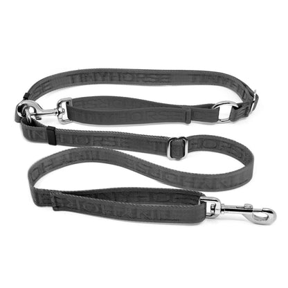 Adjustable hands-free dog leash with traffic handle. Grey with a grey colour accent in front of the hips. Attach more dogs using the rings sewn into the waist. Made of nylon embossed with “Tinyhorse.”