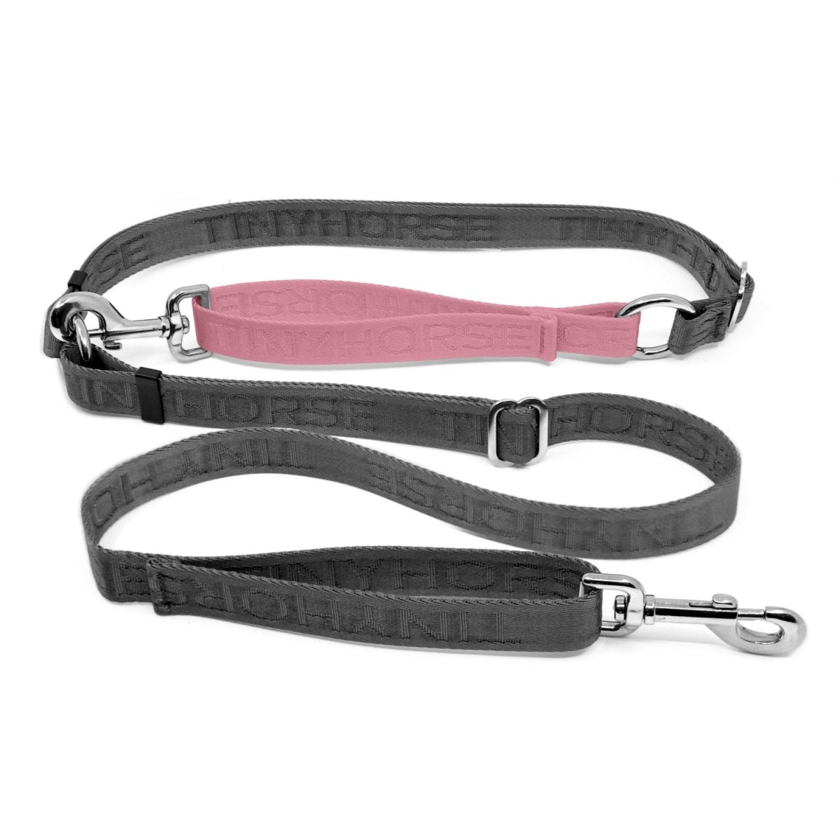 Adjustable hands-free dog leash with traffic handle. Grey with a pink colour accent in front of the hips. Attach more dogs using the rings sewn into the waist. Made of nylon embossed with “Tinyhorse.”